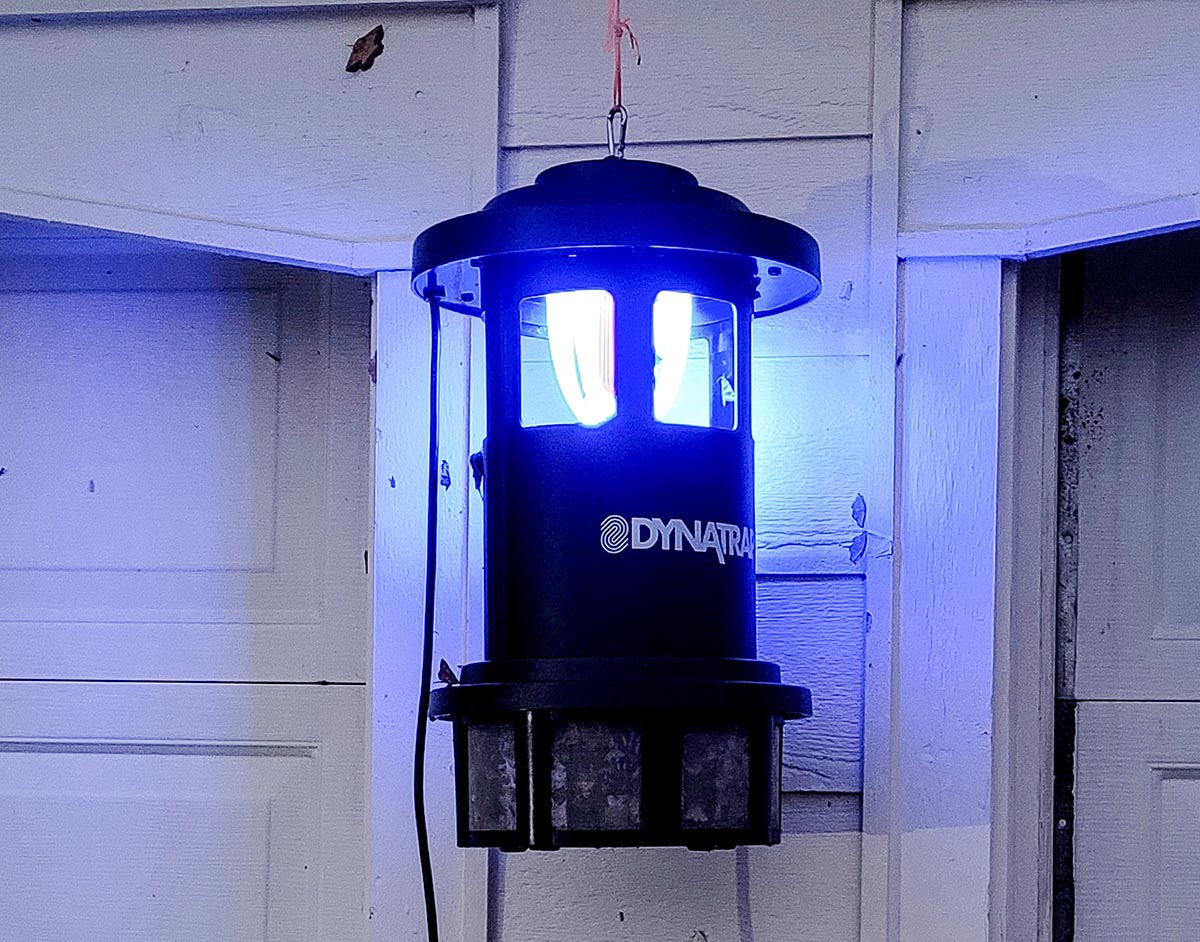 The DynaTrap insection trap glowing while installed near a garage door