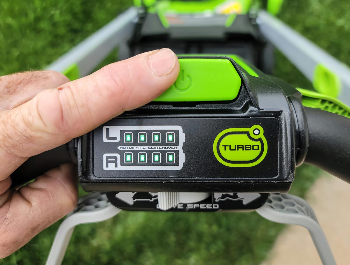 A person pushing the start button on the Greenworks Pro 60V 21-Inch Battery Lawn Mower