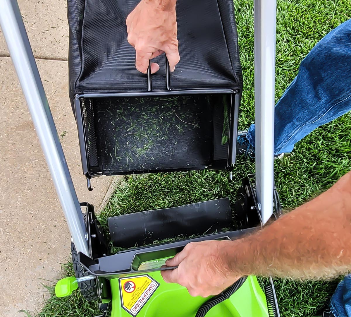 A person removing the rear bag of the Greenworks Pro 60V 21-Inch Battery Lawn Mower