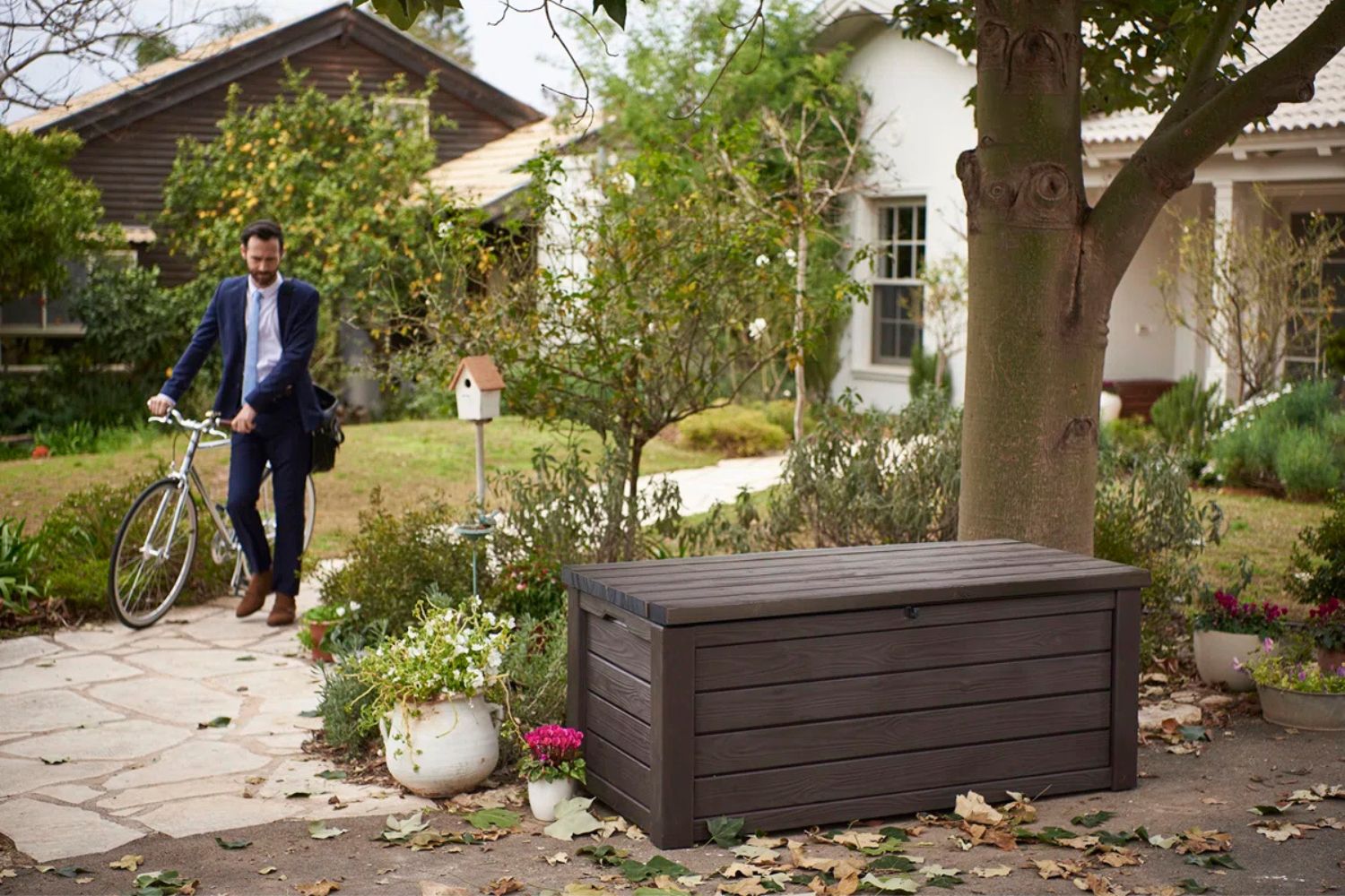 a man in a garden with Keter Eastwood 150-Gallon Deck Box