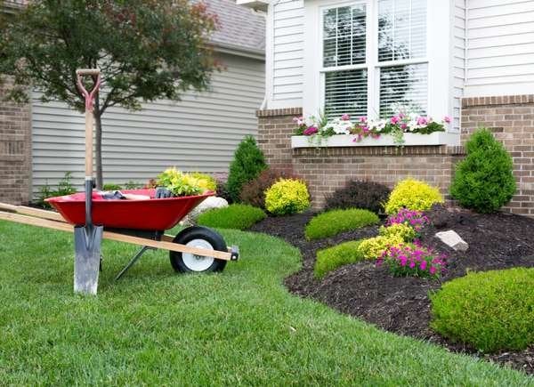 Wheelbarrow on a lawn with materials to plant in new planting bed