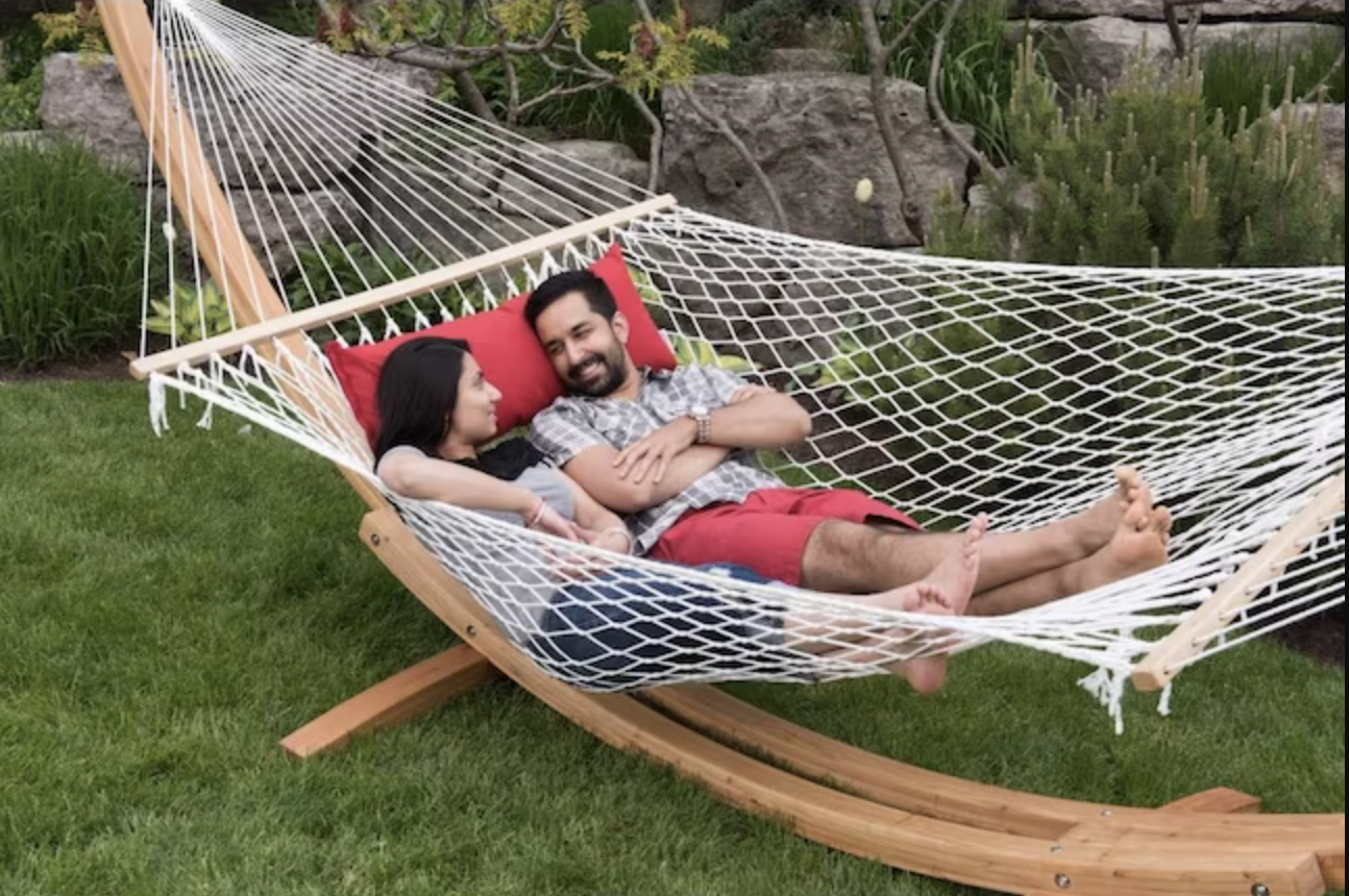 Man and a woman on a two-person hammock in the backyard