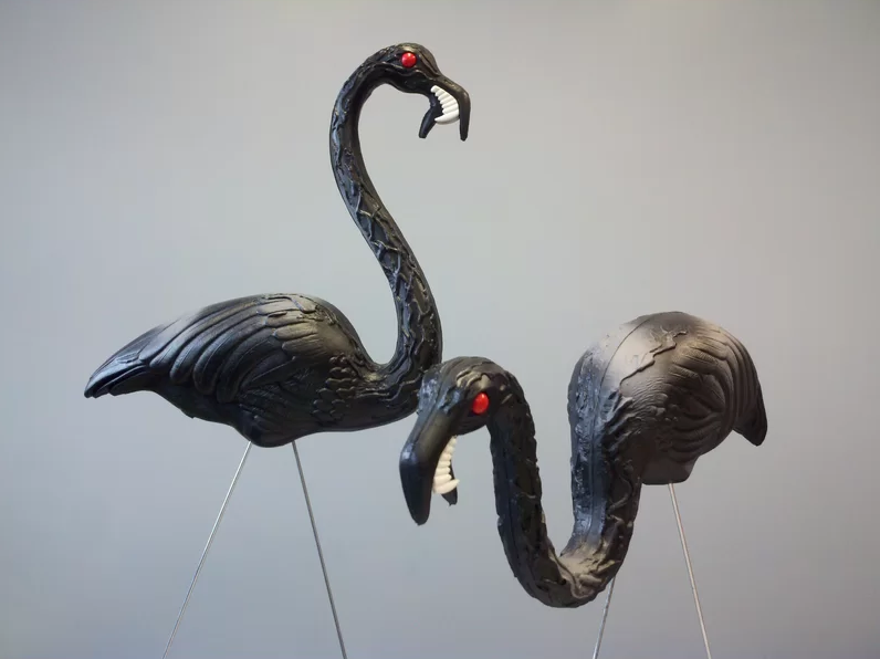 two black plastic flamingos with fangs and red eyes
