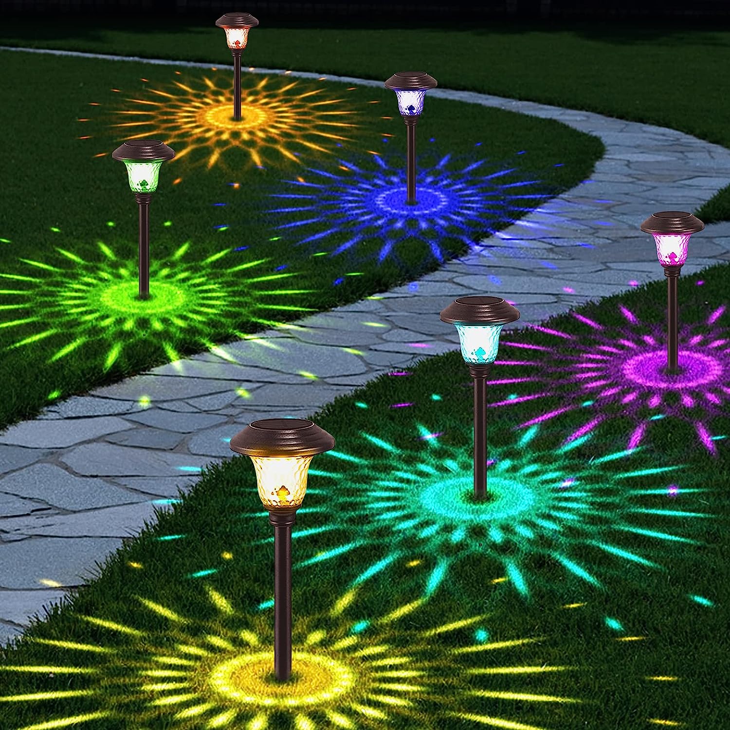 winding stone pathway lit by multi colored pathway lights casting patterns on the grass