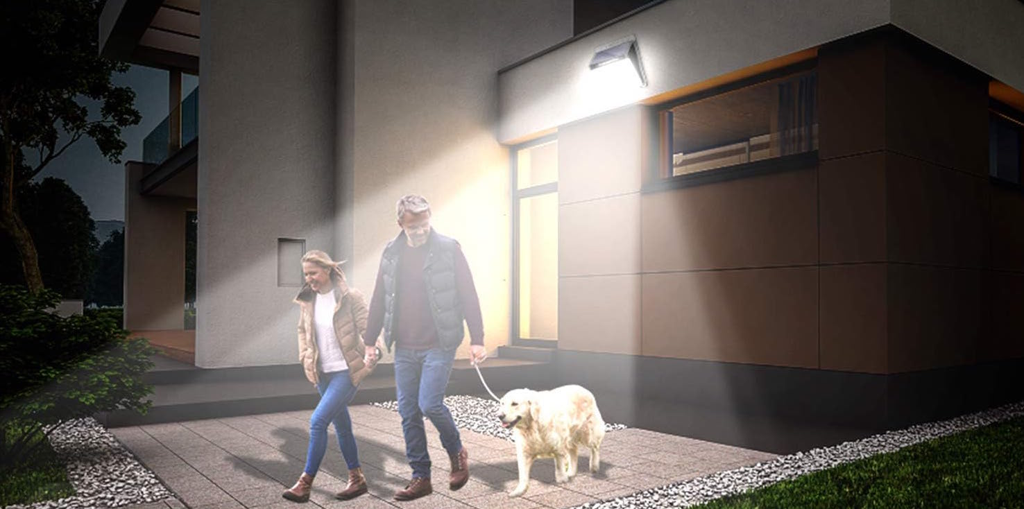 mockup of couple walking outside modern house on driveway lit by large led light walking dog