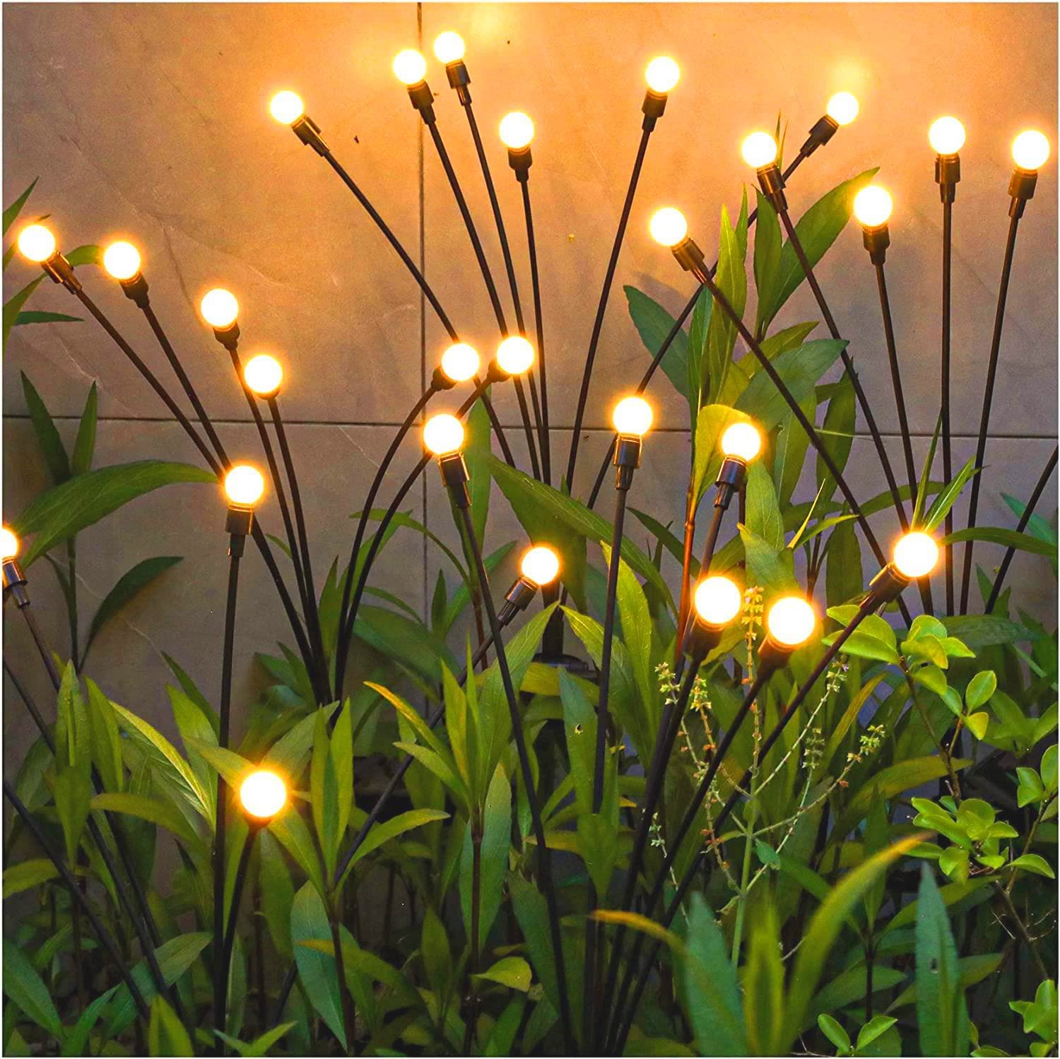 close shot of small stake lights shaped like blades of grass among plants in garden