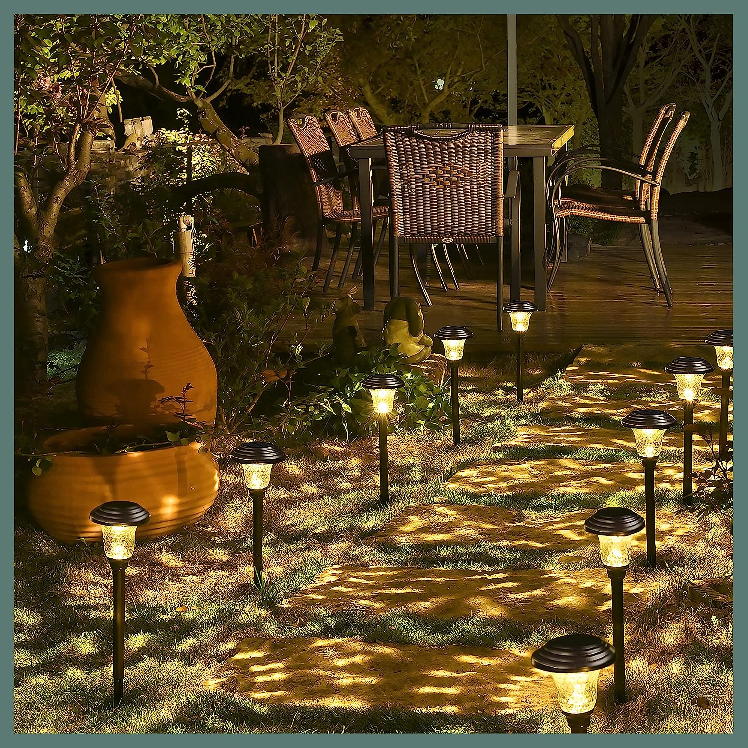 backyard patio with stone pathway lit by small lights leading to table and chairs