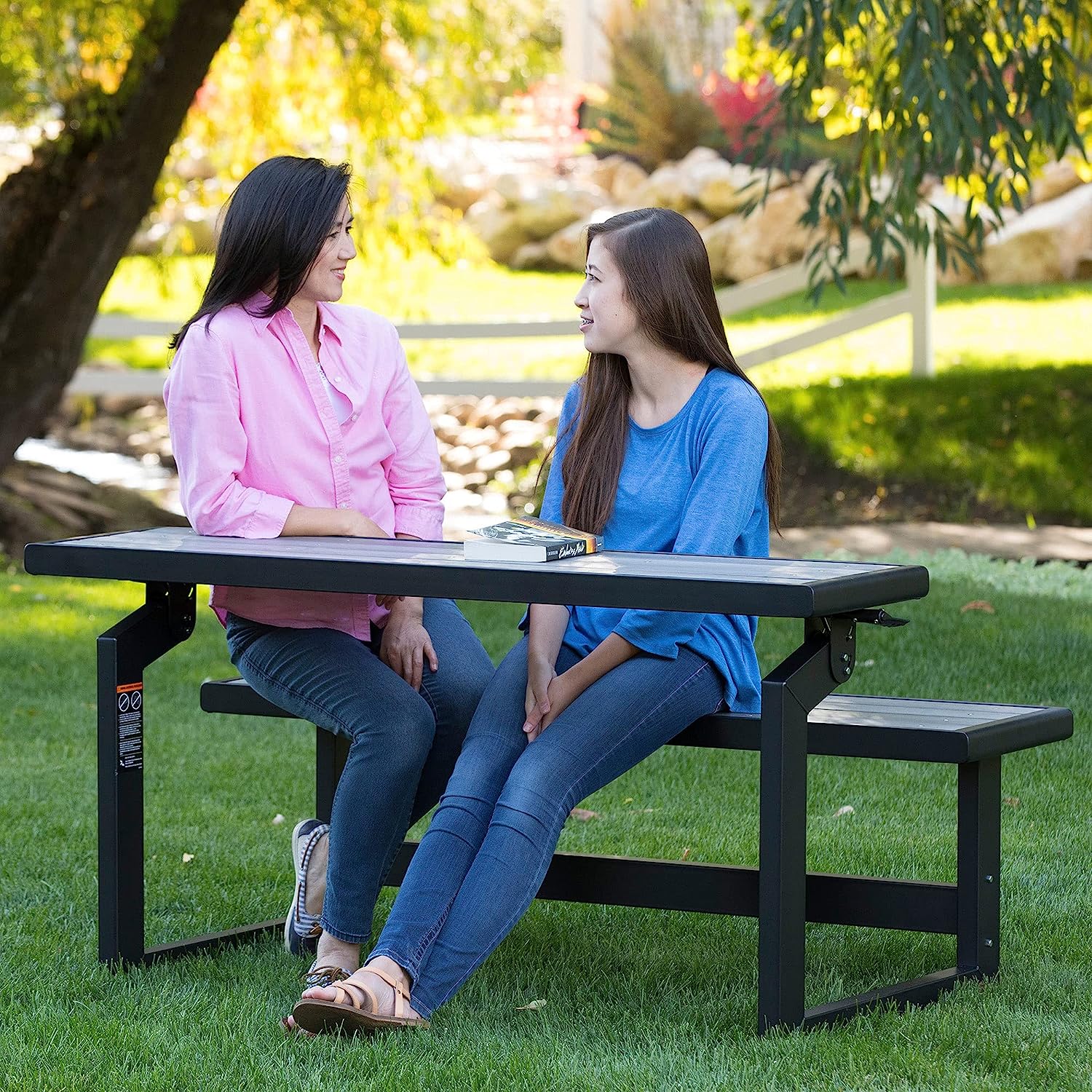 Convertible garden bench with two women chatting and sitting on it.