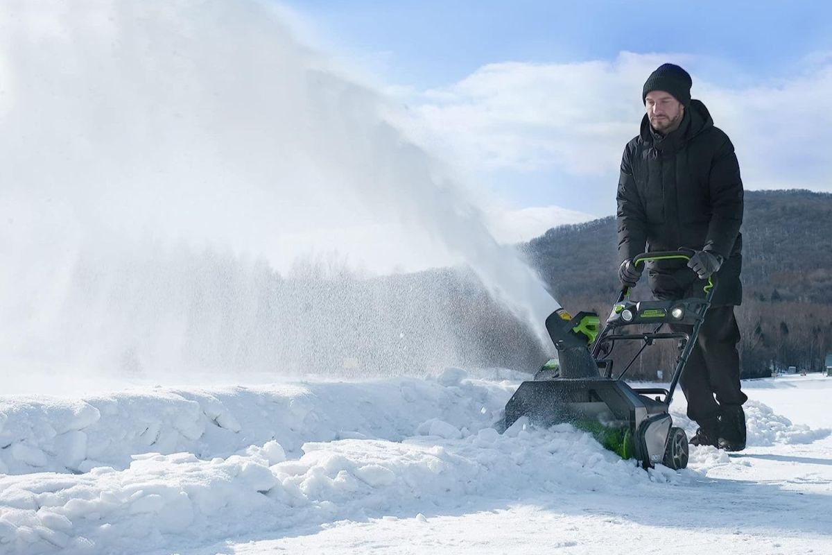 A person using the best cheap snow blower option to clear a path in snow