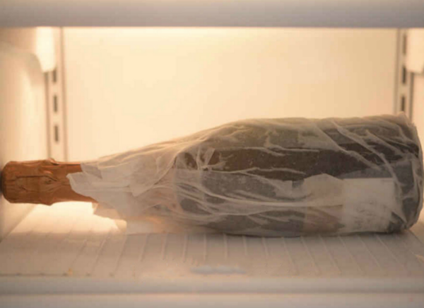 wet paper towel wrapped around champagne bottle in freezer