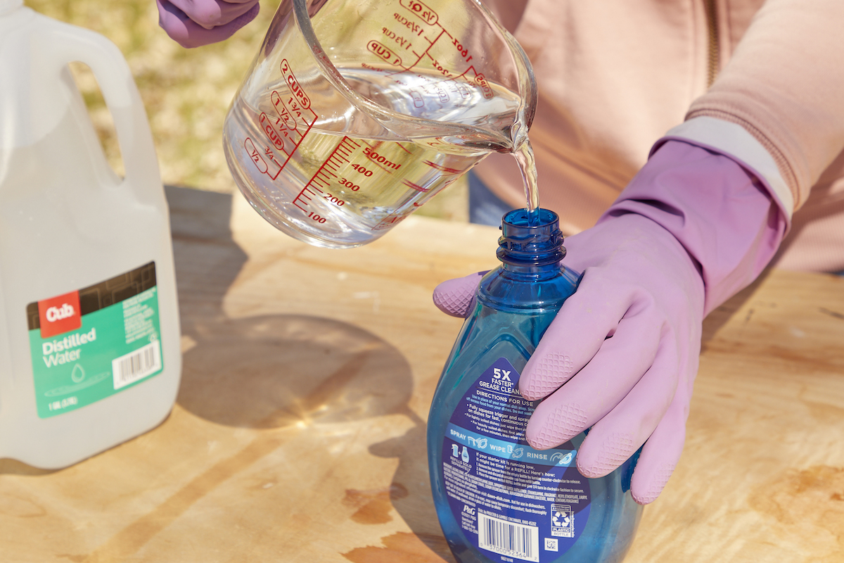 Woman pours distilled water into a Dawn Powerwash bottle.
