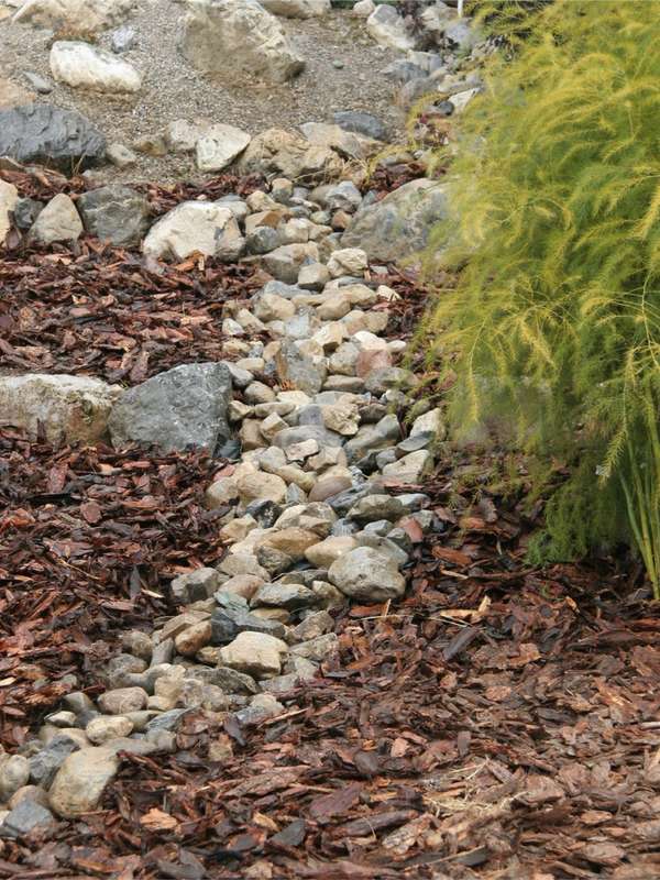 A dry creek bed of river rock and mulch.