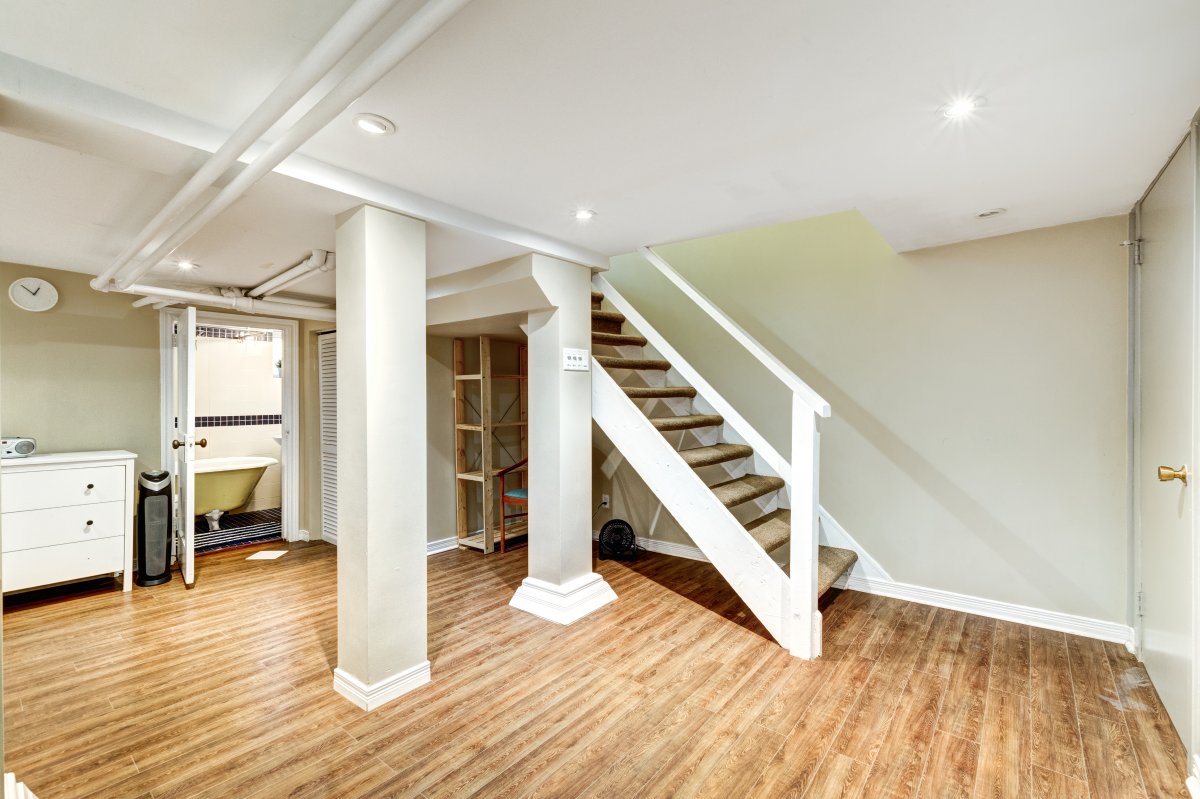Open finished basement with staircase and neutral paint on the walls.