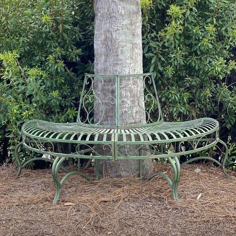 Metal garden bench wrapping around large tree.