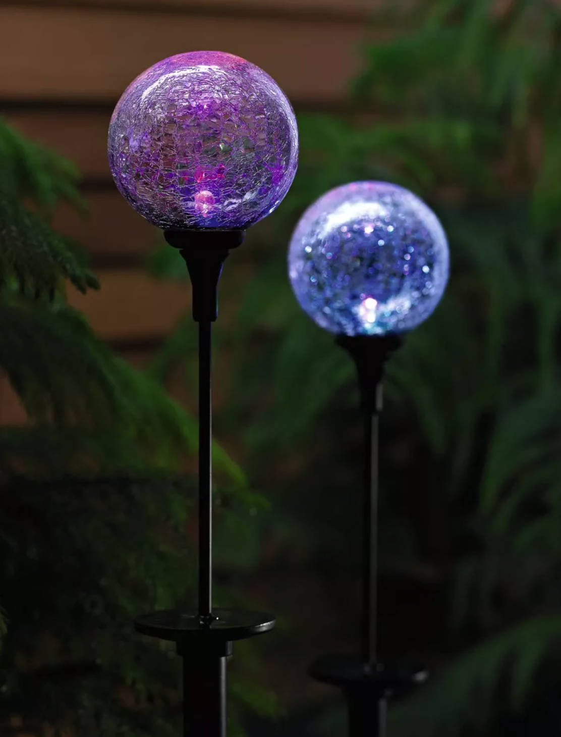 close up on two small stake lights with blue and purple orbs in garden