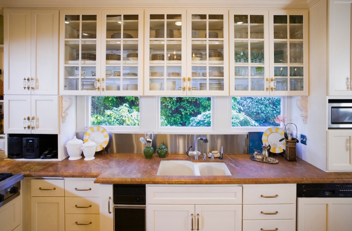 Traditional kitchen with glass-front upper ktichen cabinets and a brown stone countertop.