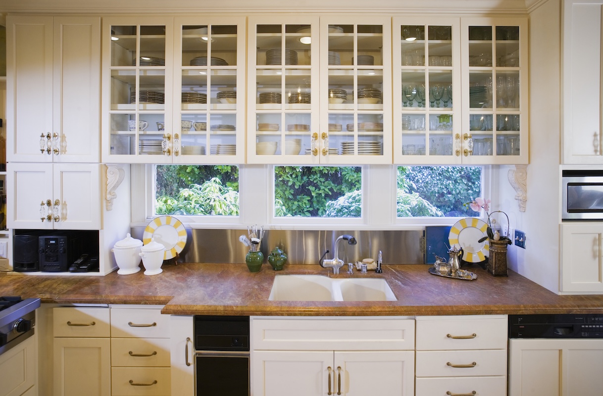 Traditional kitchen with glass-front upper ktichen cabinets and a brown stone countertop.