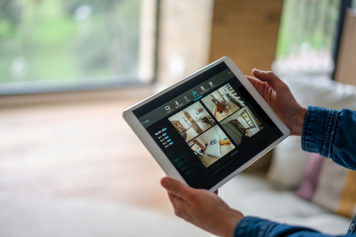 A person holds a tablet with different angles of home security footage.