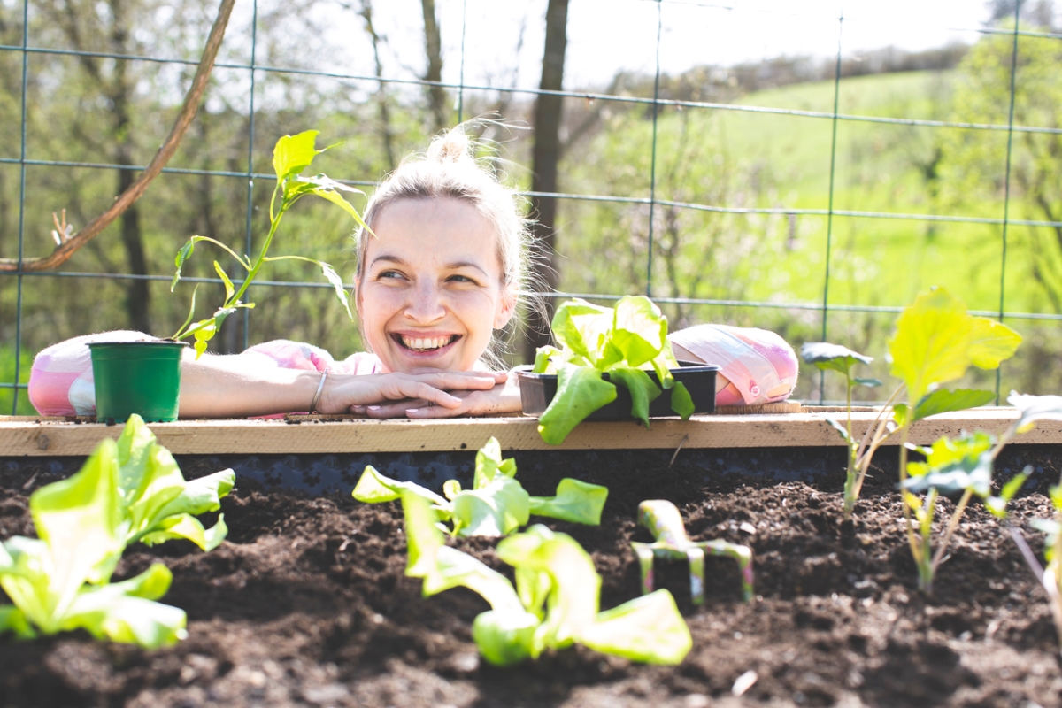 Woman smiling around plants in raised garden