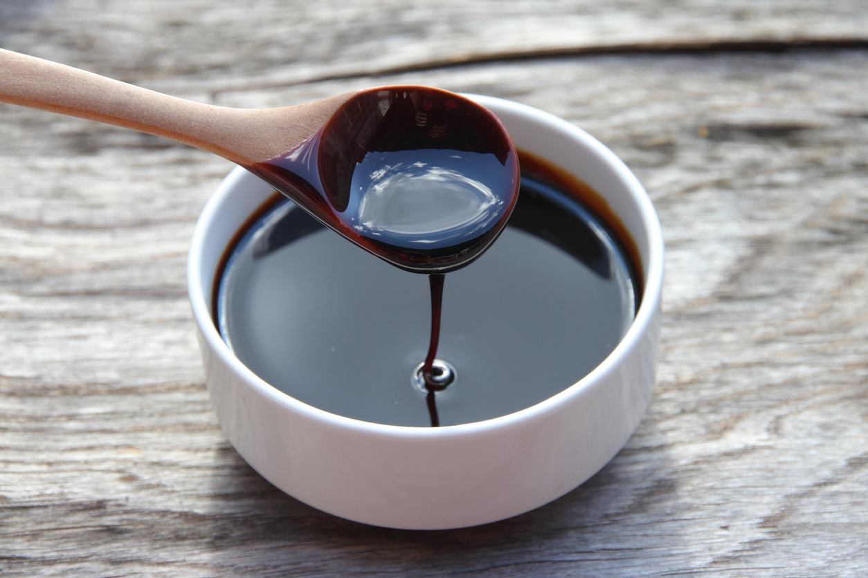 close view of bowl full of blackstrap molasses with spoon scooping a string of molasses