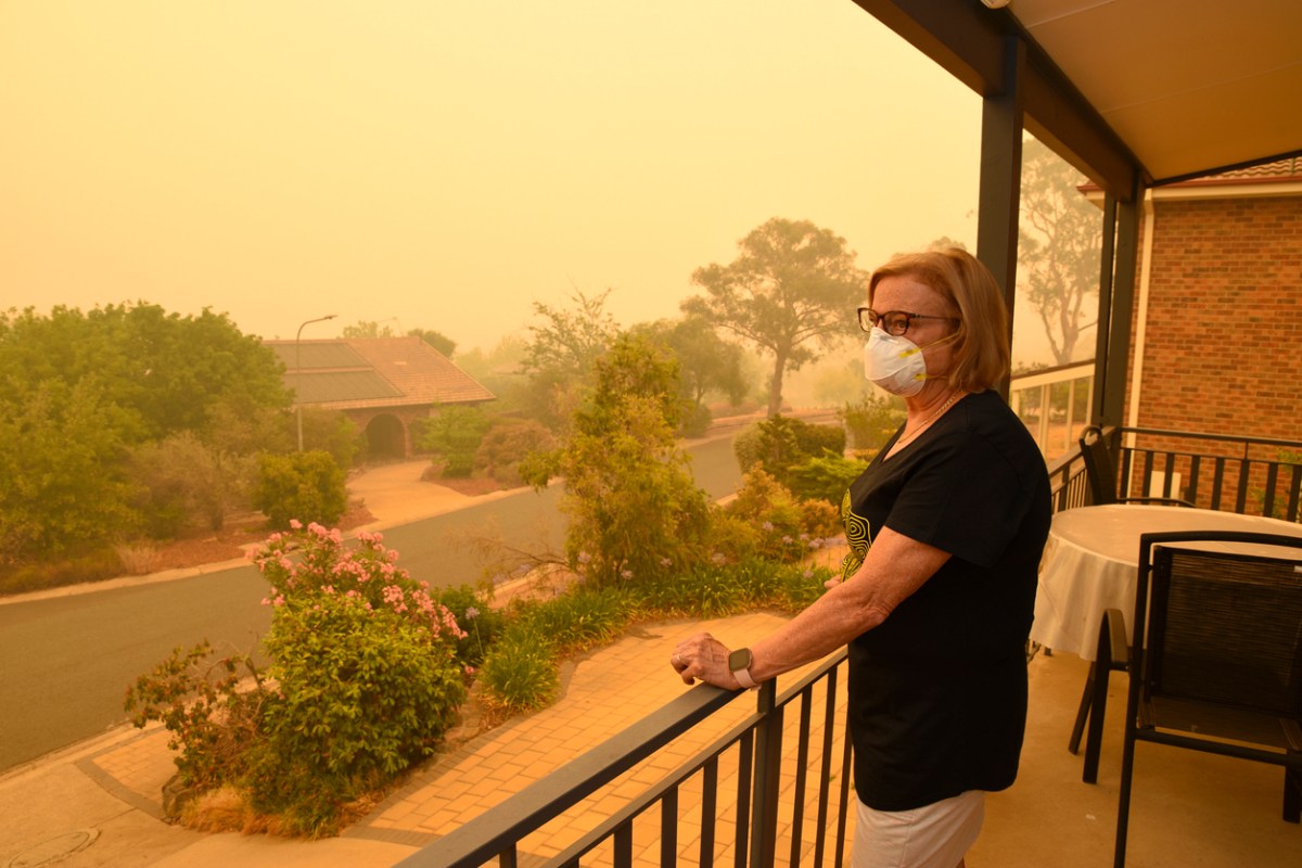 woman-wearing-a-face-mask-looks-out-over-the-neighborhood-with-wildfire-smoke-in-the-air
