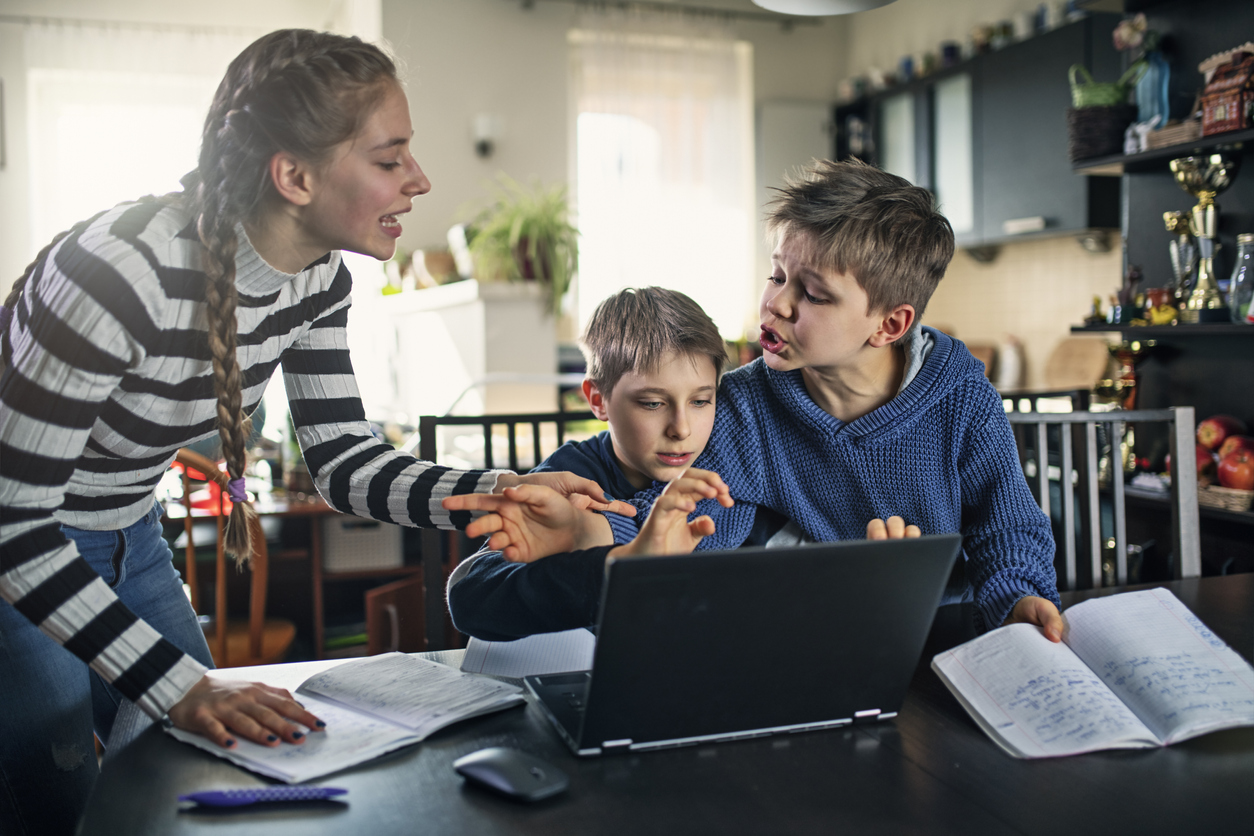 three siblings in home office arguing over laptop