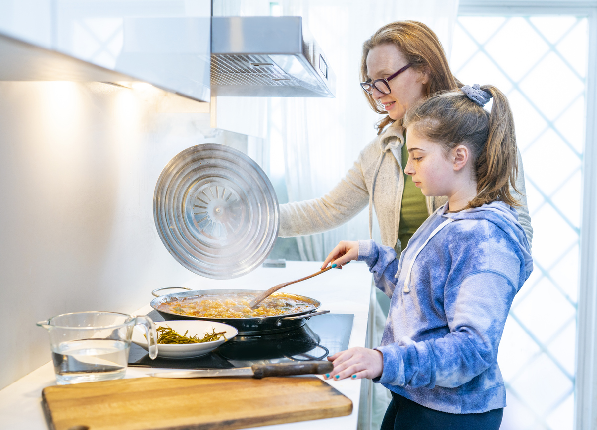 side view of mother and daughter cooking at stove with smoke in kitchen
