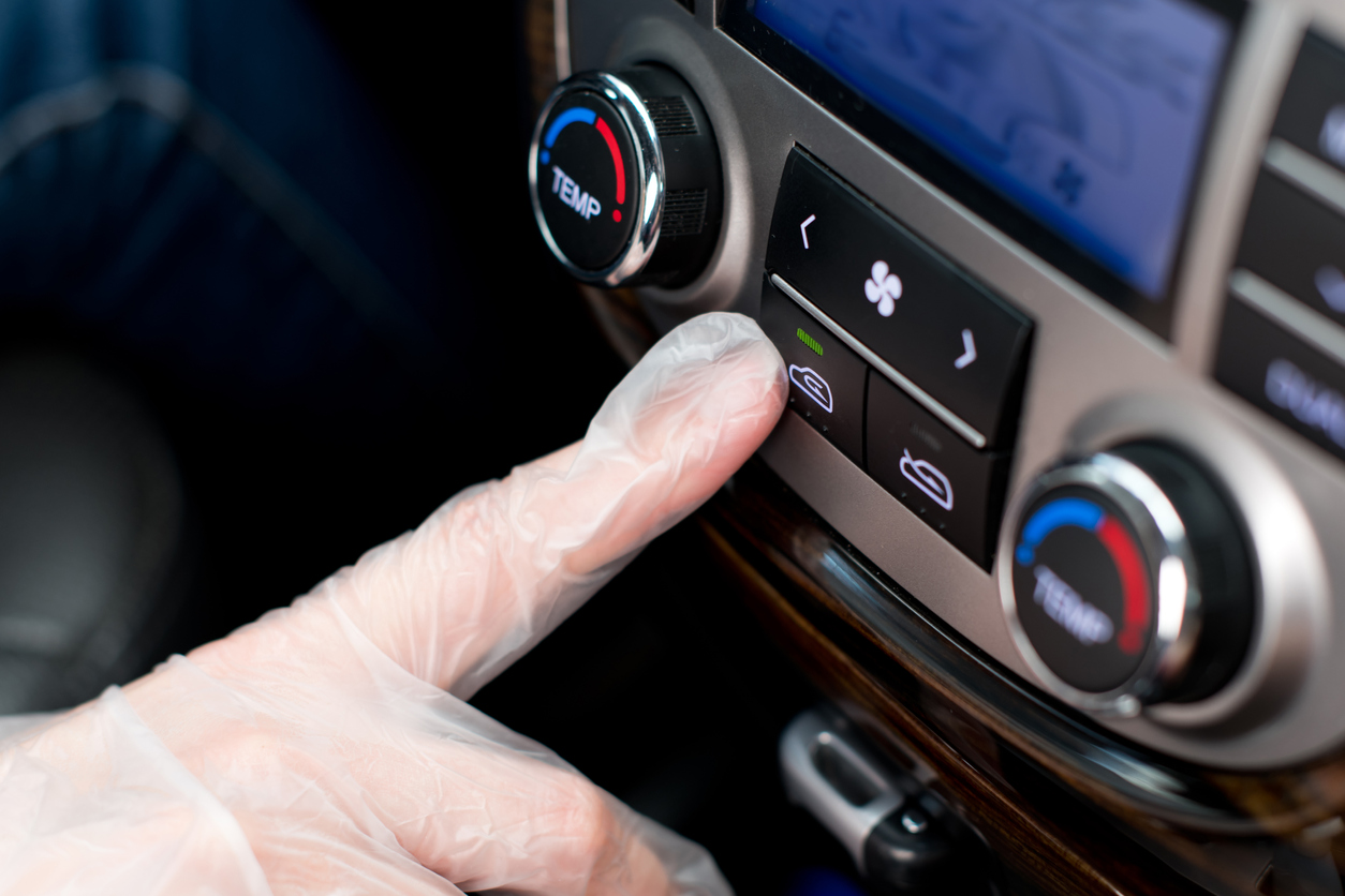 a hand in a medical glove presses the air recirculation button in the car