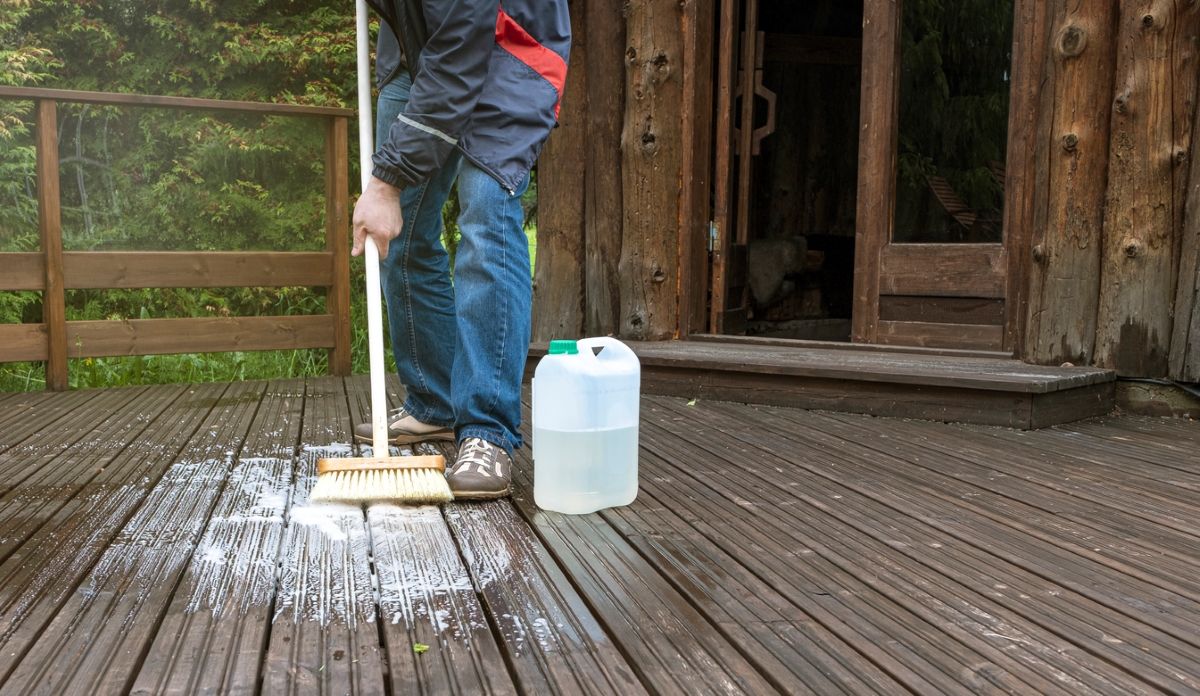 Person cleaning deck with soap and broom