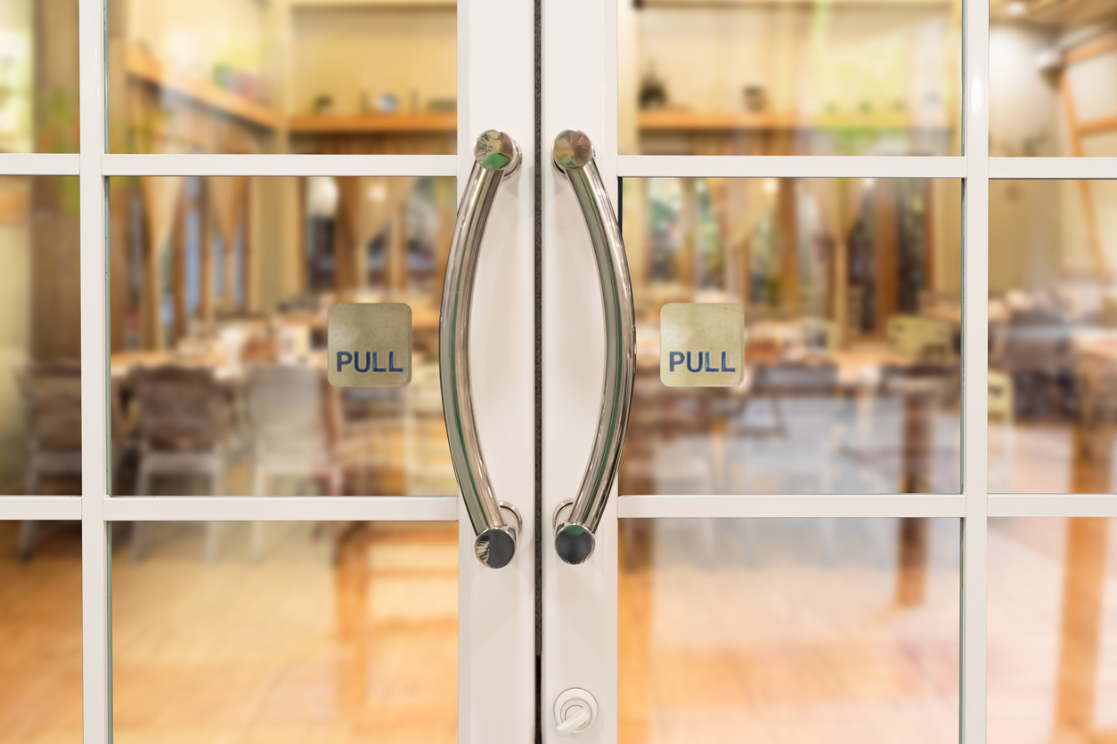 glass double doors to restaurant with ornate handles and pull signs on each door