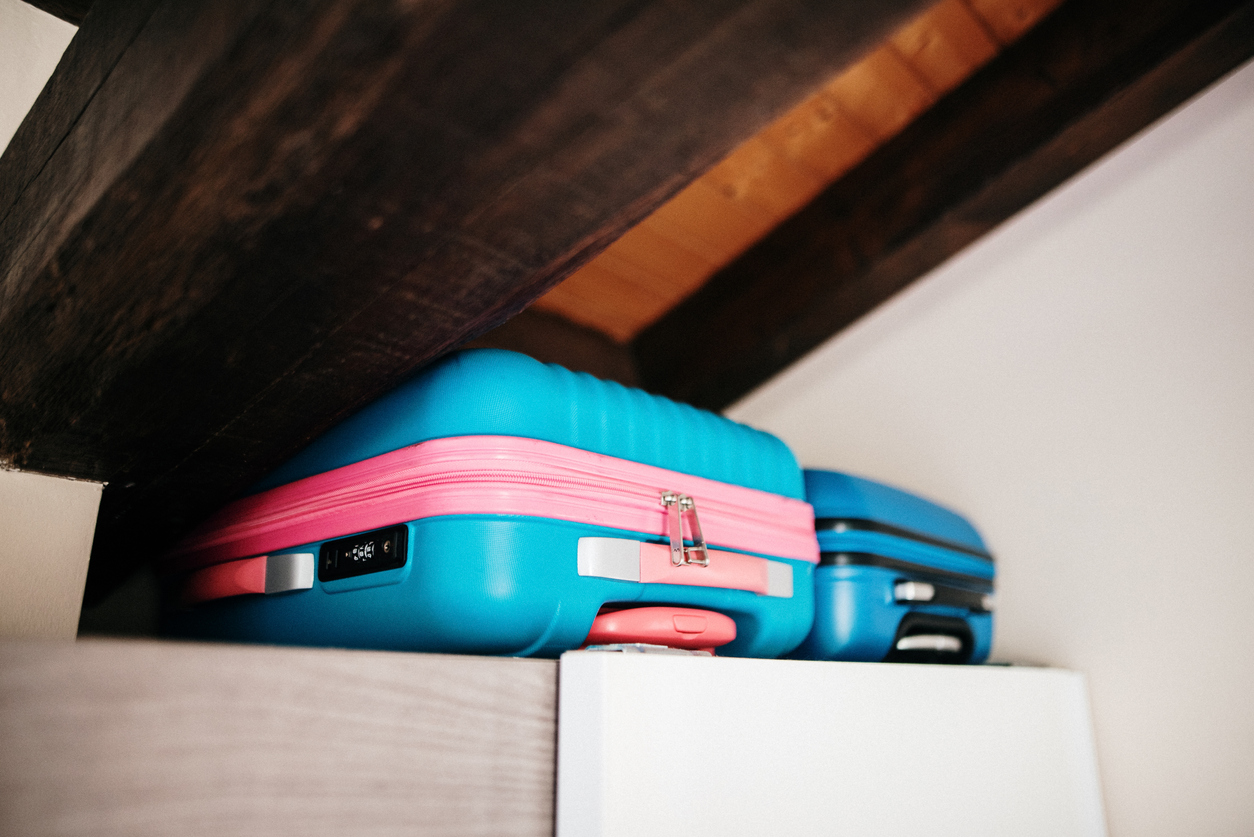 blue and pink suitcases in storage in attic crawl space