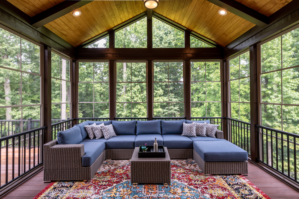 enlcosed sun room with blue patio furniture and persian rug with glass walls and roof providing shade