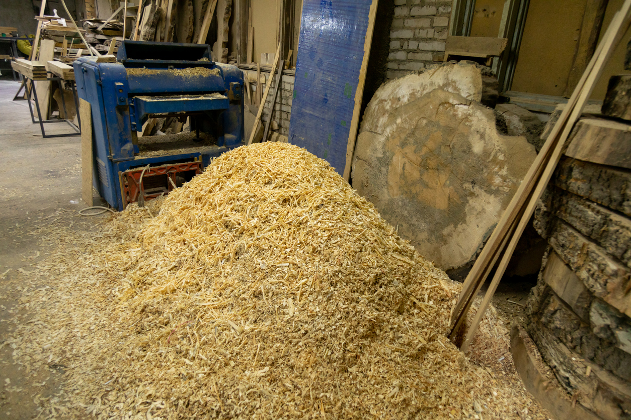 Sawdust pile near woodworking machine in workshop