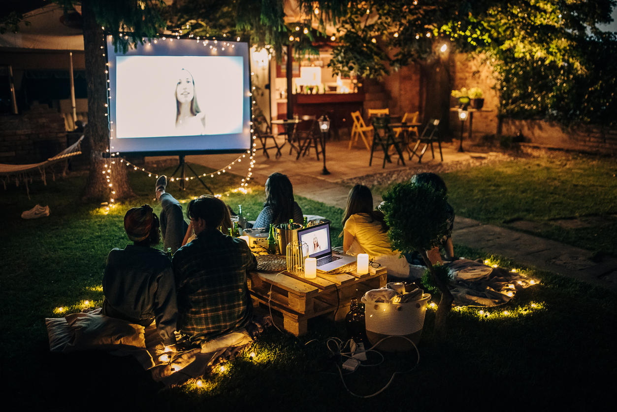 Friends watching movie on the video projector in the backyard garden