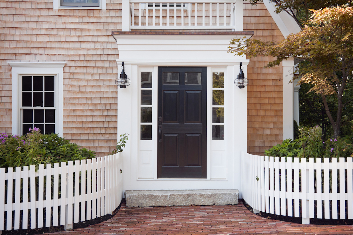cedar shake house with curved white picket fence leading to the front door