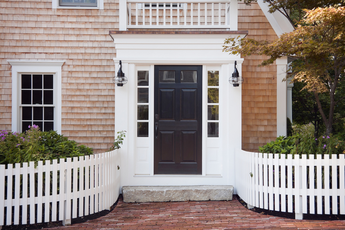 cedar shake house with curved white picket fence leading to the front door
