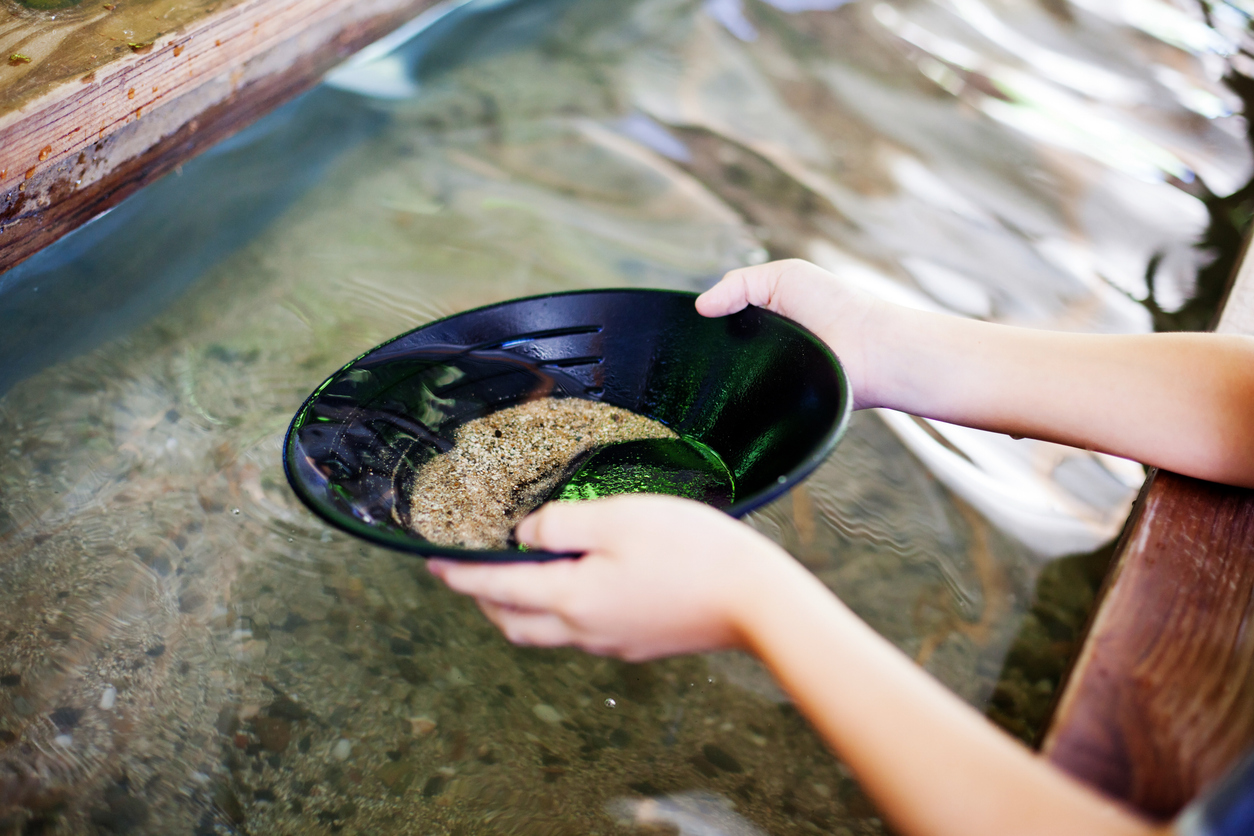 close up on young woman's hands holding dish full of water and minerals panning for gold