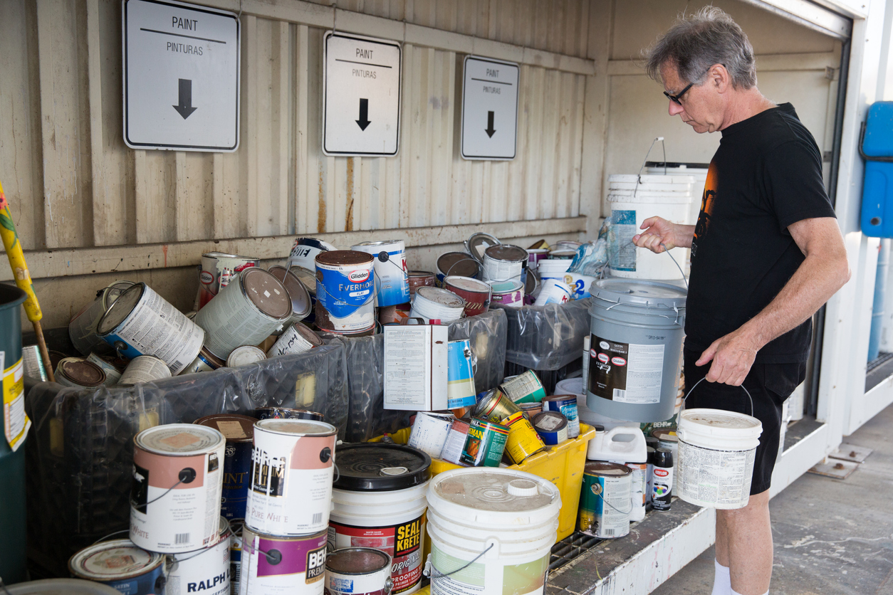 Senior man drops off old paint cans at the recycling center