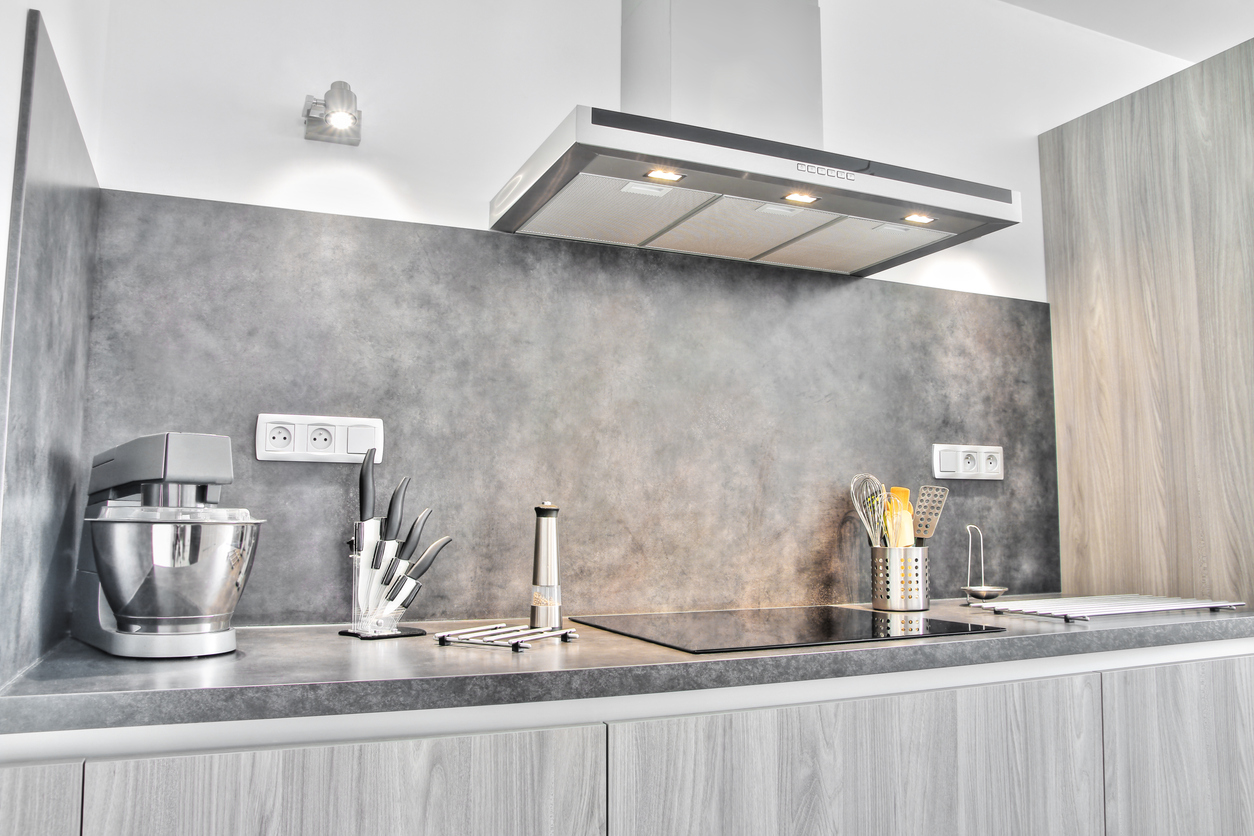 modern grey kitchen with appliances on counter and stove with range hood with lights on