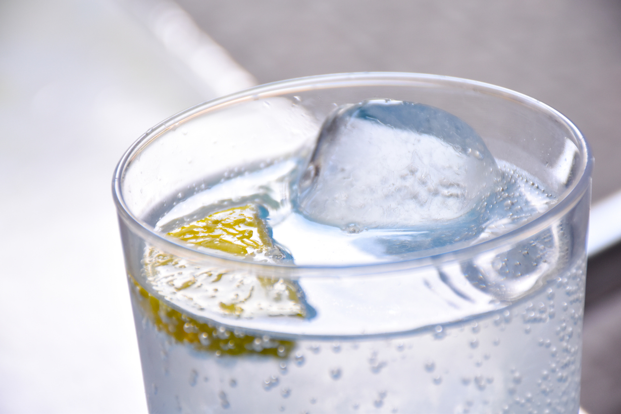 close shot of glass with ice and club soda with a lemon slice