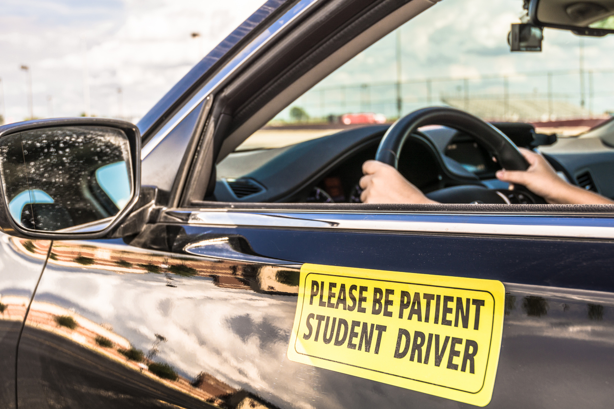 close view on drivers side of vehicle with please be patient student driver sign