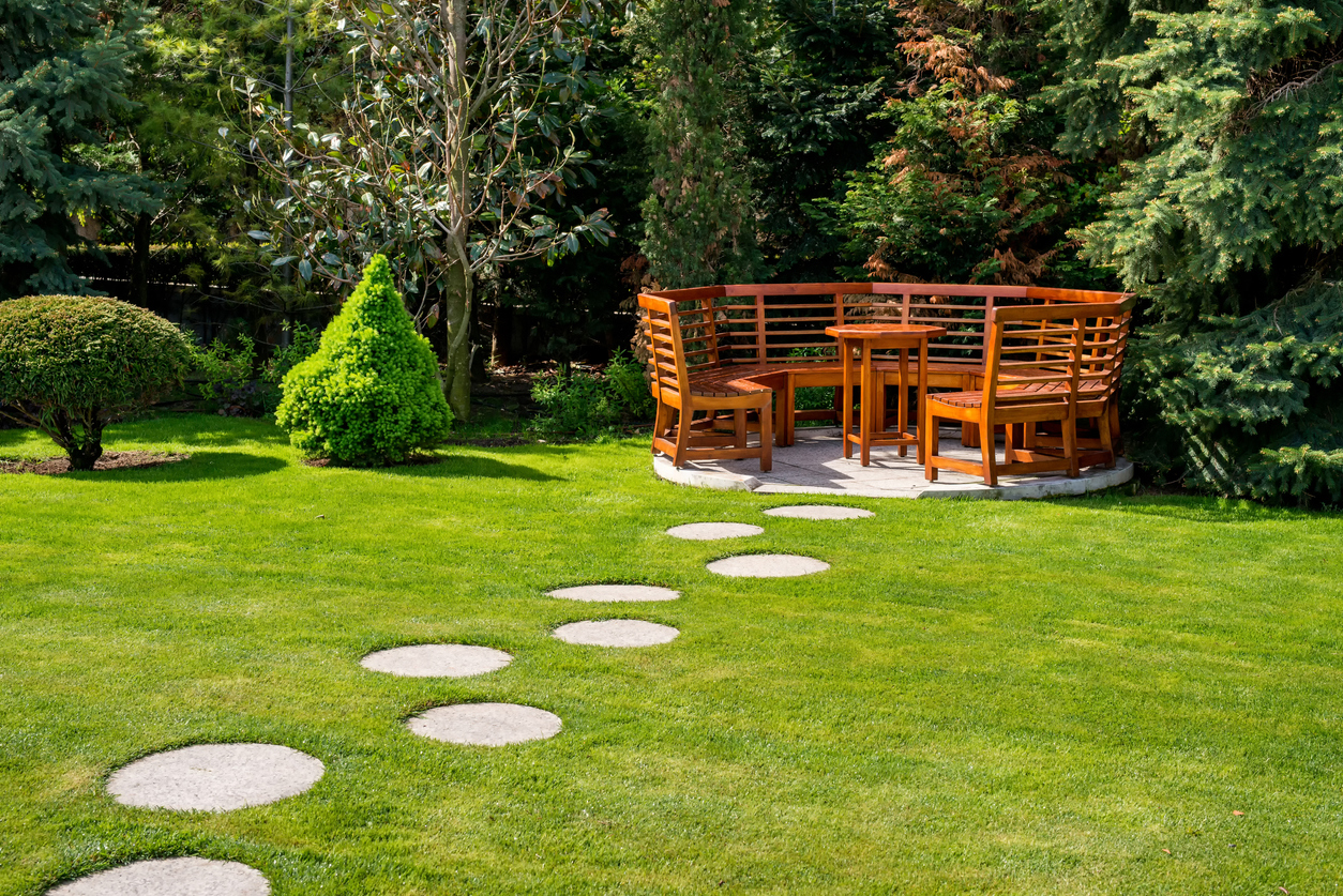 Large wooden garden bench in circular shape with high backs.