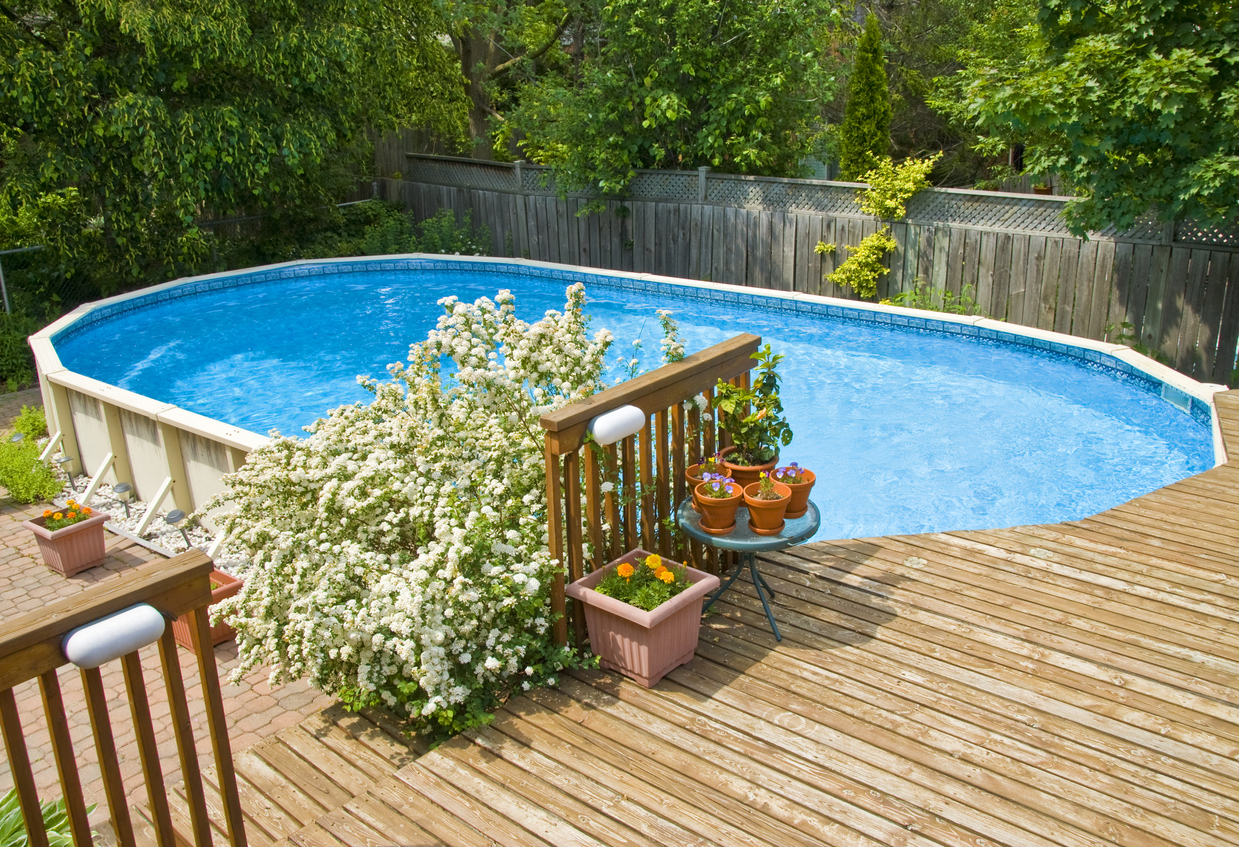 Above ground swimming pool built into deck and surrounded with small river stones