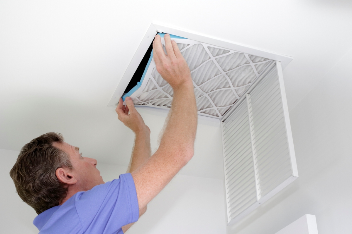 Man replacing air filter on ceiling