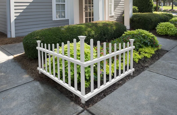 small picket fence section in front yard flower bed