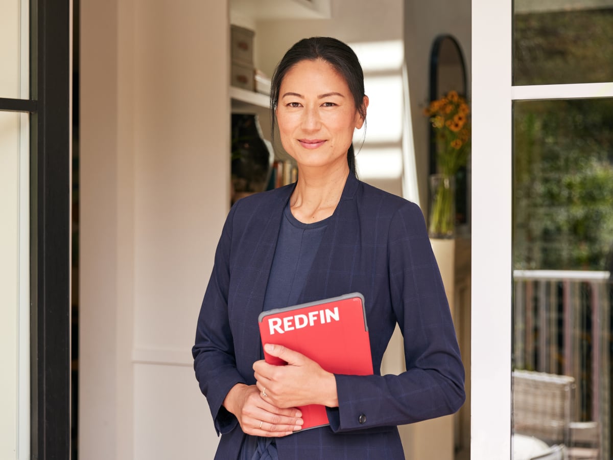 Asian woman realtor holding Redfin red tablet