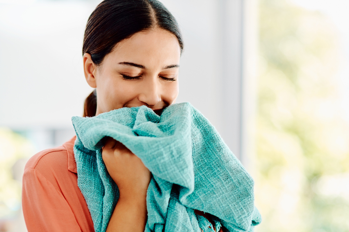 Woman smelling a freshly laundered teal-colored towel
