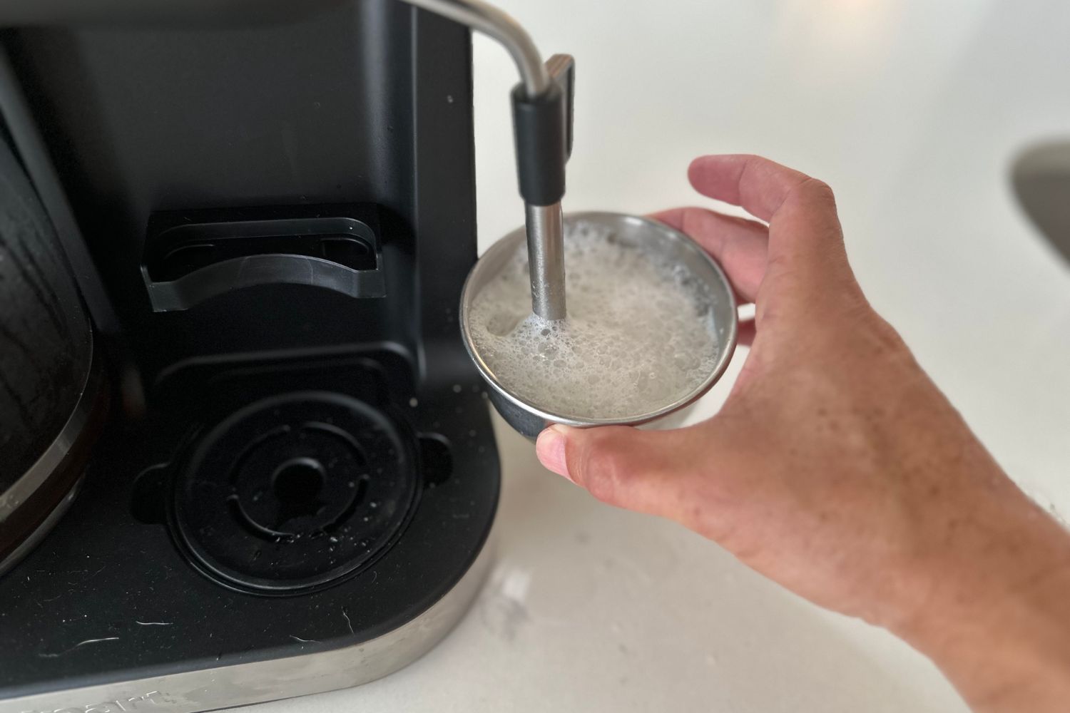 Someone frothing milk using the Cuisinart Coffee Center Barista Bar 4-in-1 Coffeemaker