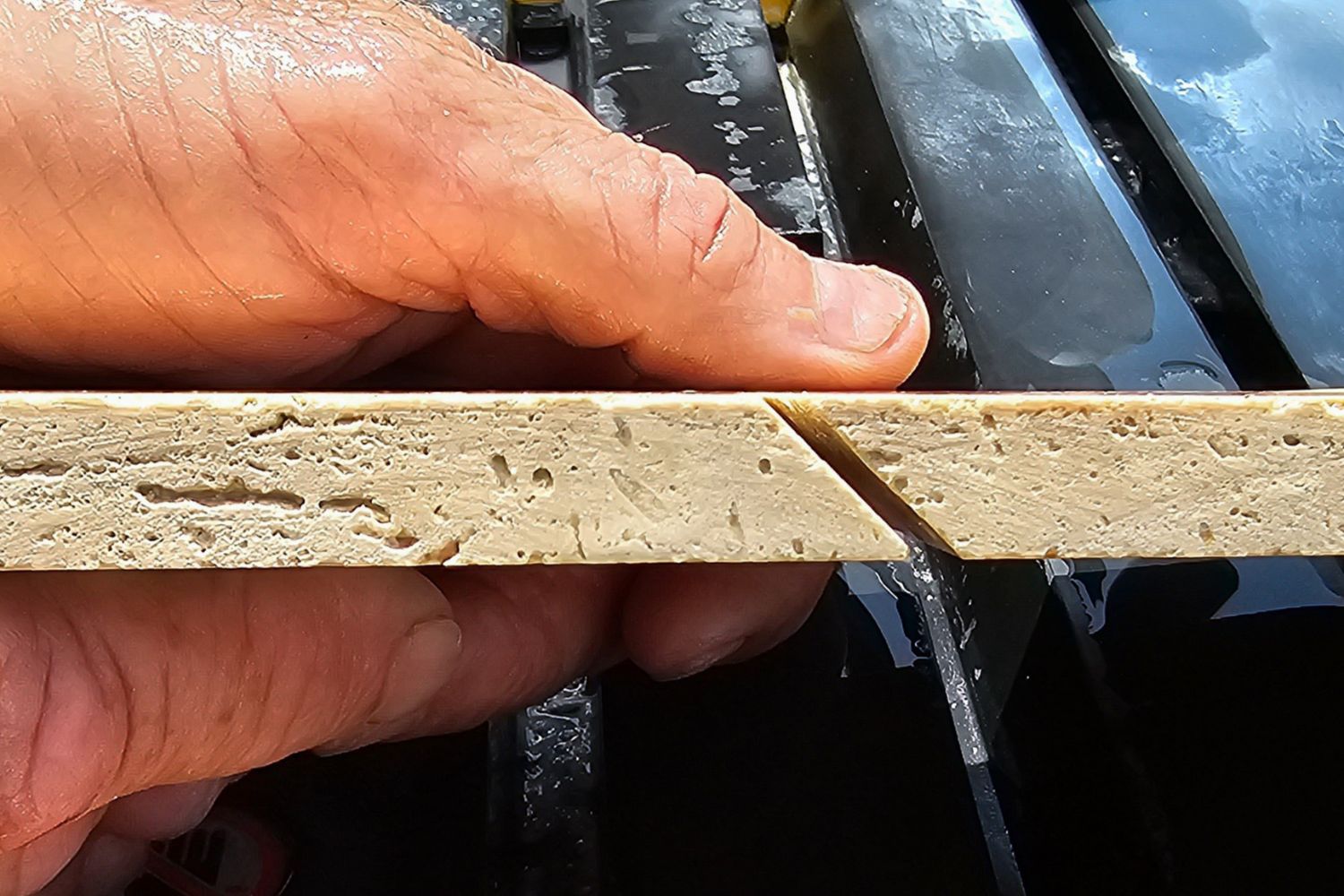 A person showing the edge of a tile that's been cut at a 45-degree angle using the DeWalt 10-inch wet tile saw