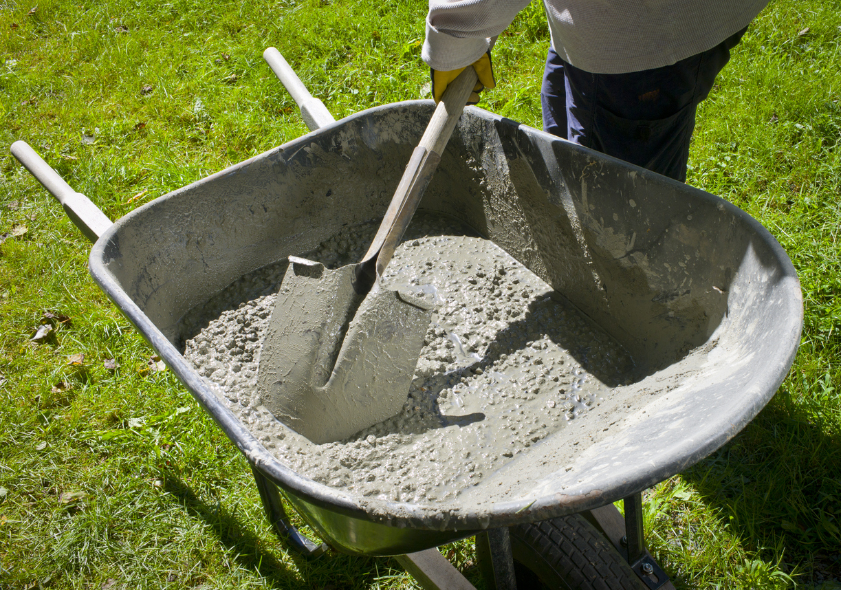 Mixing concrete mix in a wheelbarrow with a shovel
